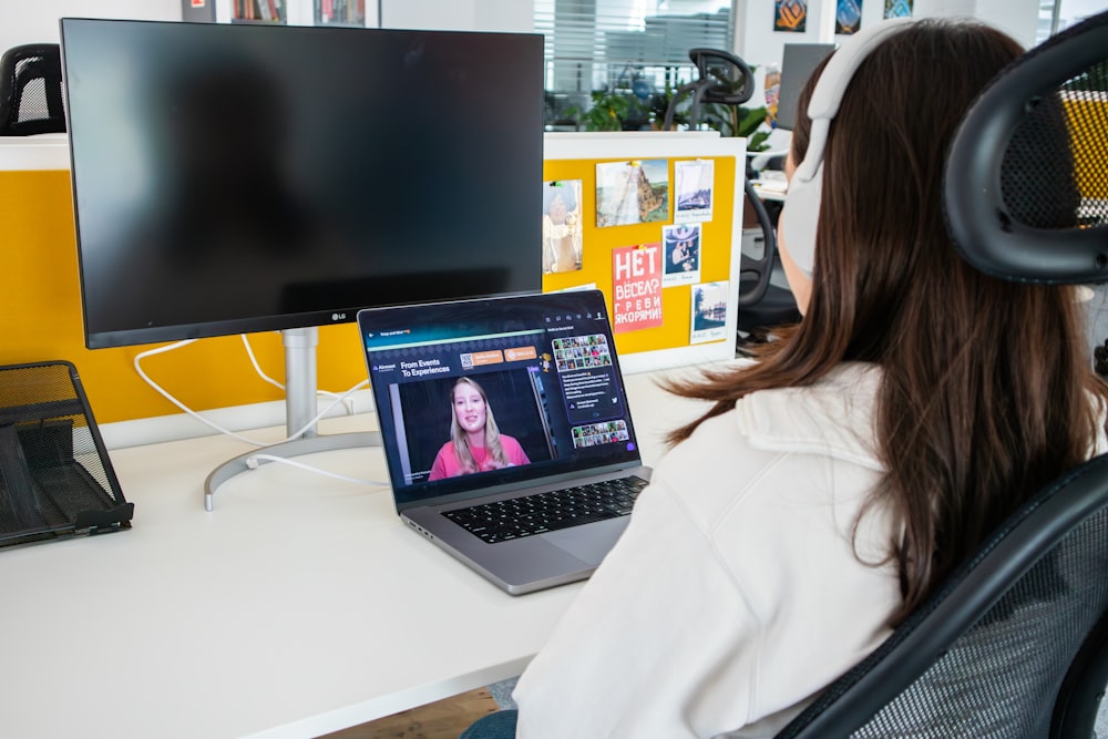 a woman sitting in front of a computer monitor