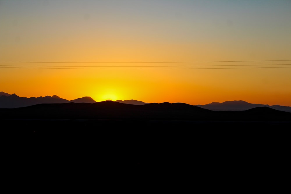 the sun is setting over the mountains in the distance