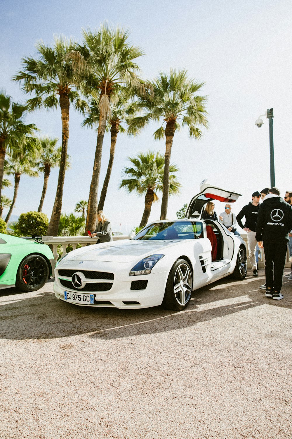 a group of people standing around a white sports car