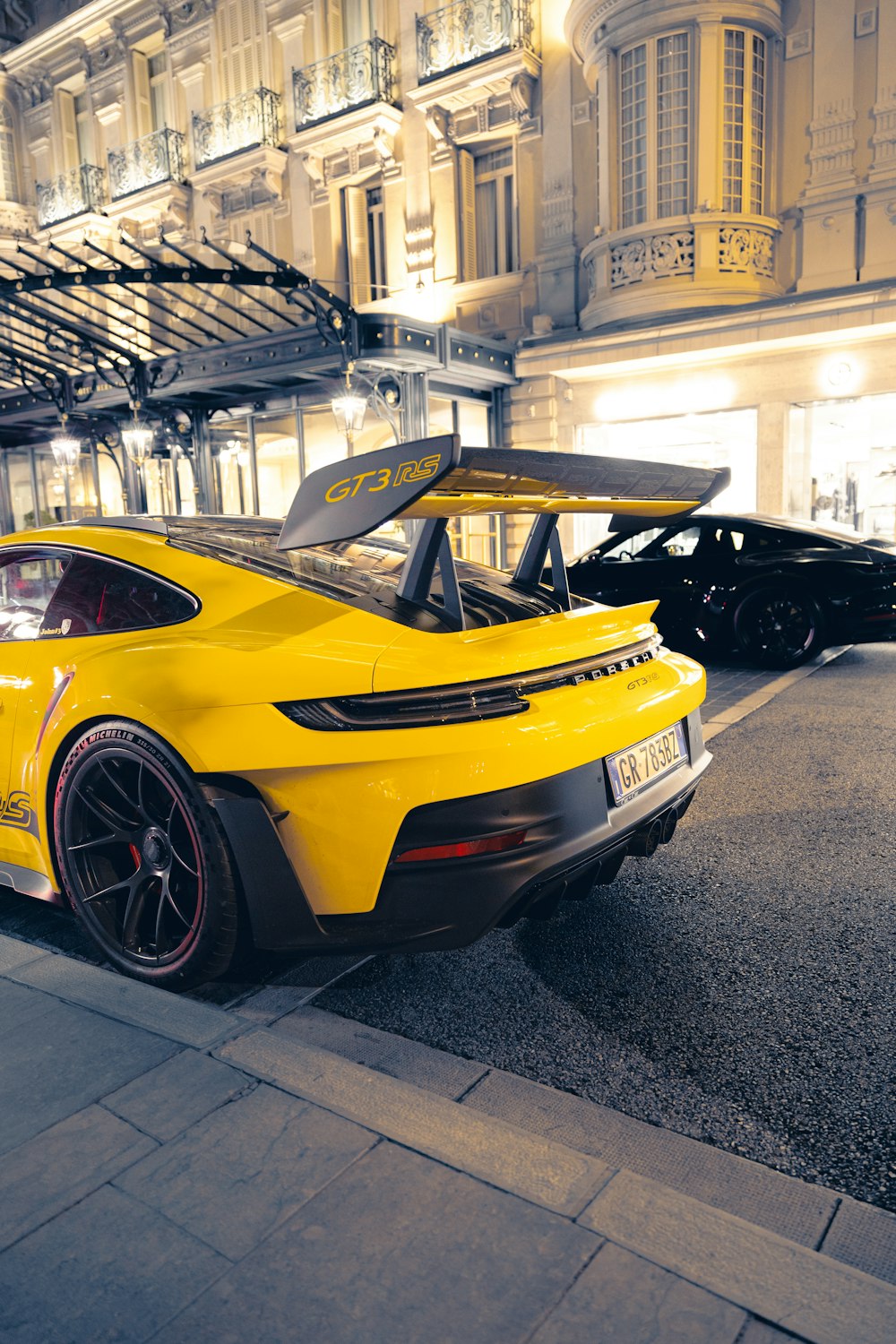 a yellow sports car parked in front of a building