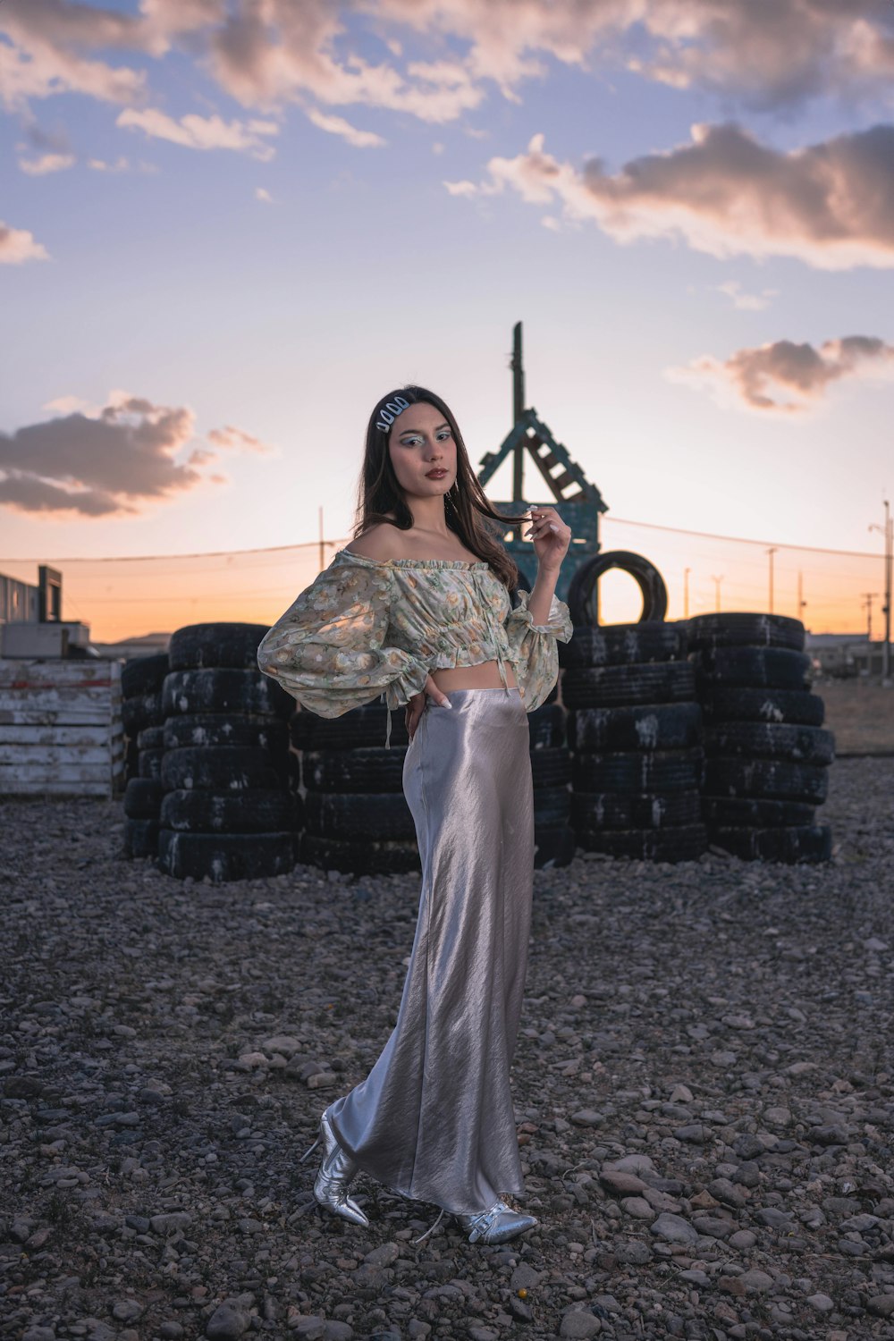 a woman standing in a field next to a pile of tires