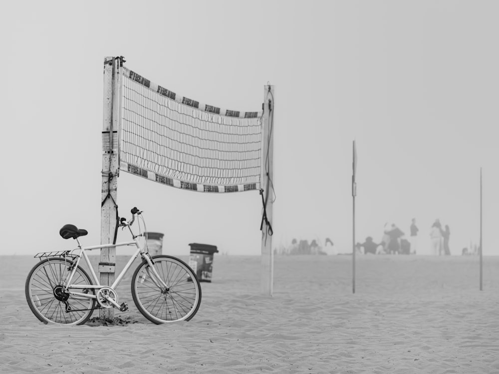 a bicycle parked next to a volleyball net on a beach