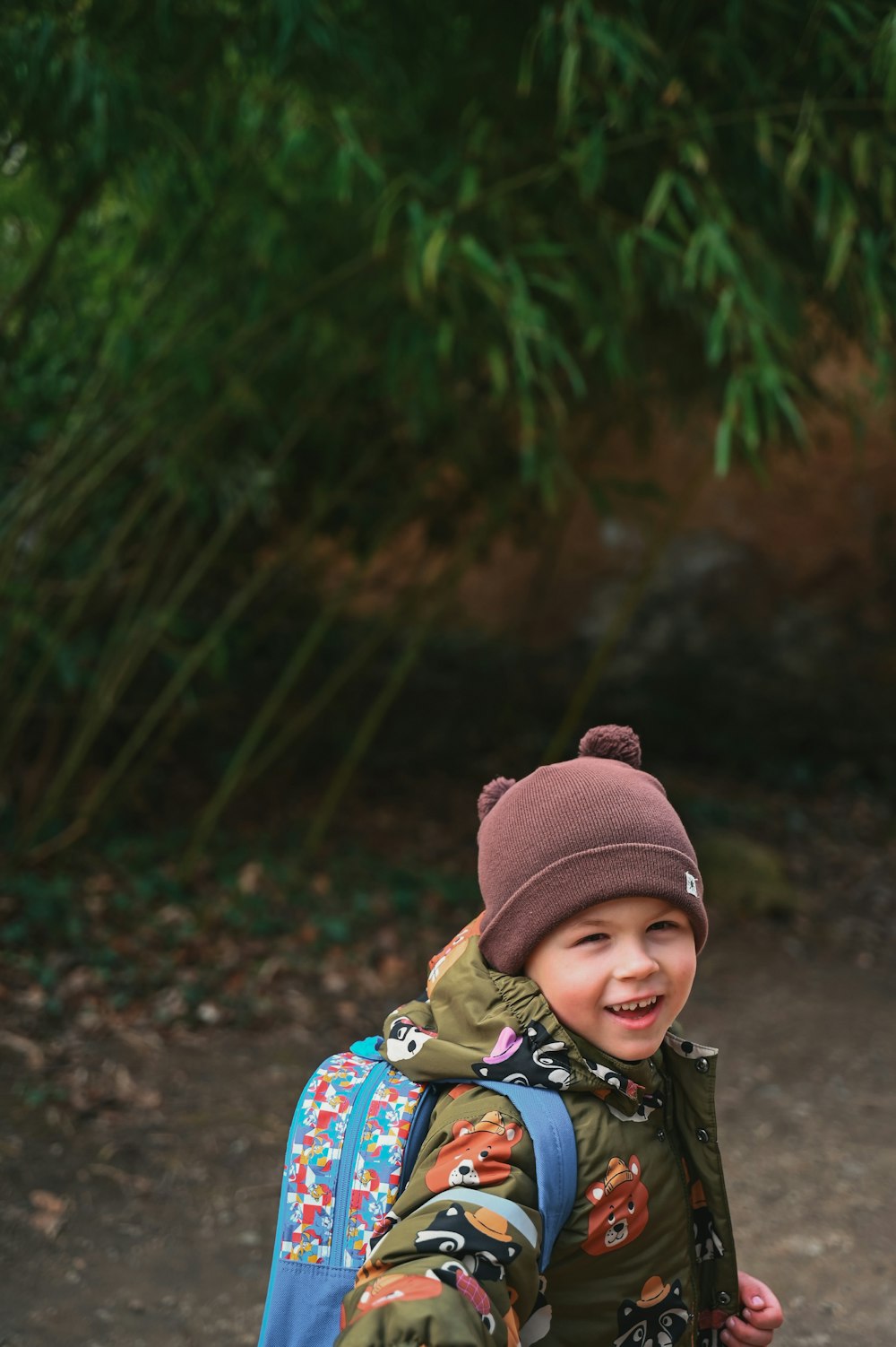 a young boy wearing a backpack and a hat