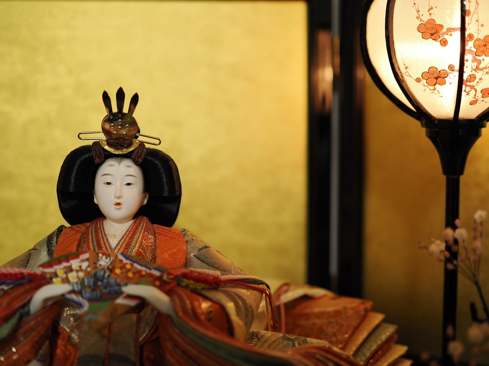 a figurine of a geisha sitting next to a lamp