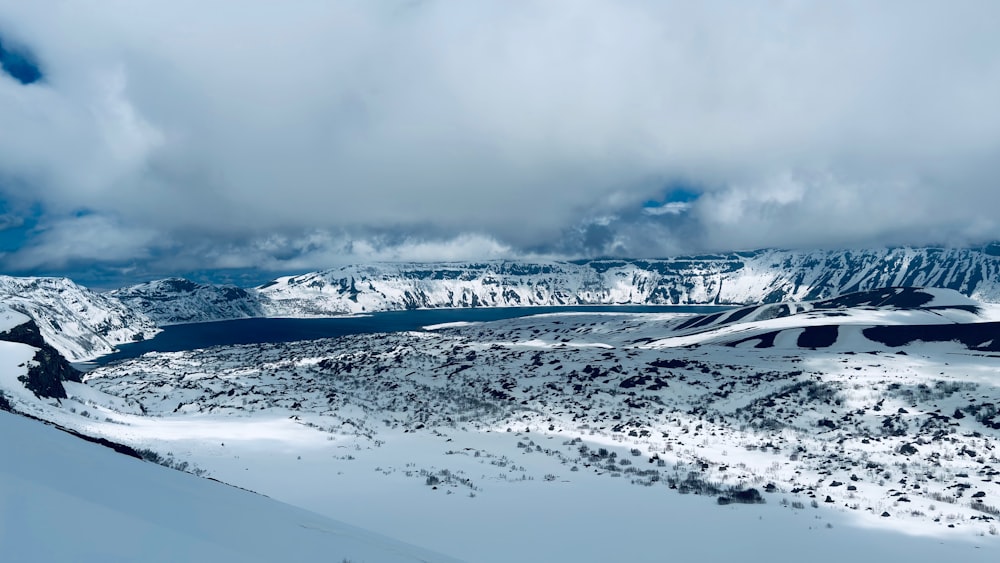 a snow covered mountain with a lake in the distance