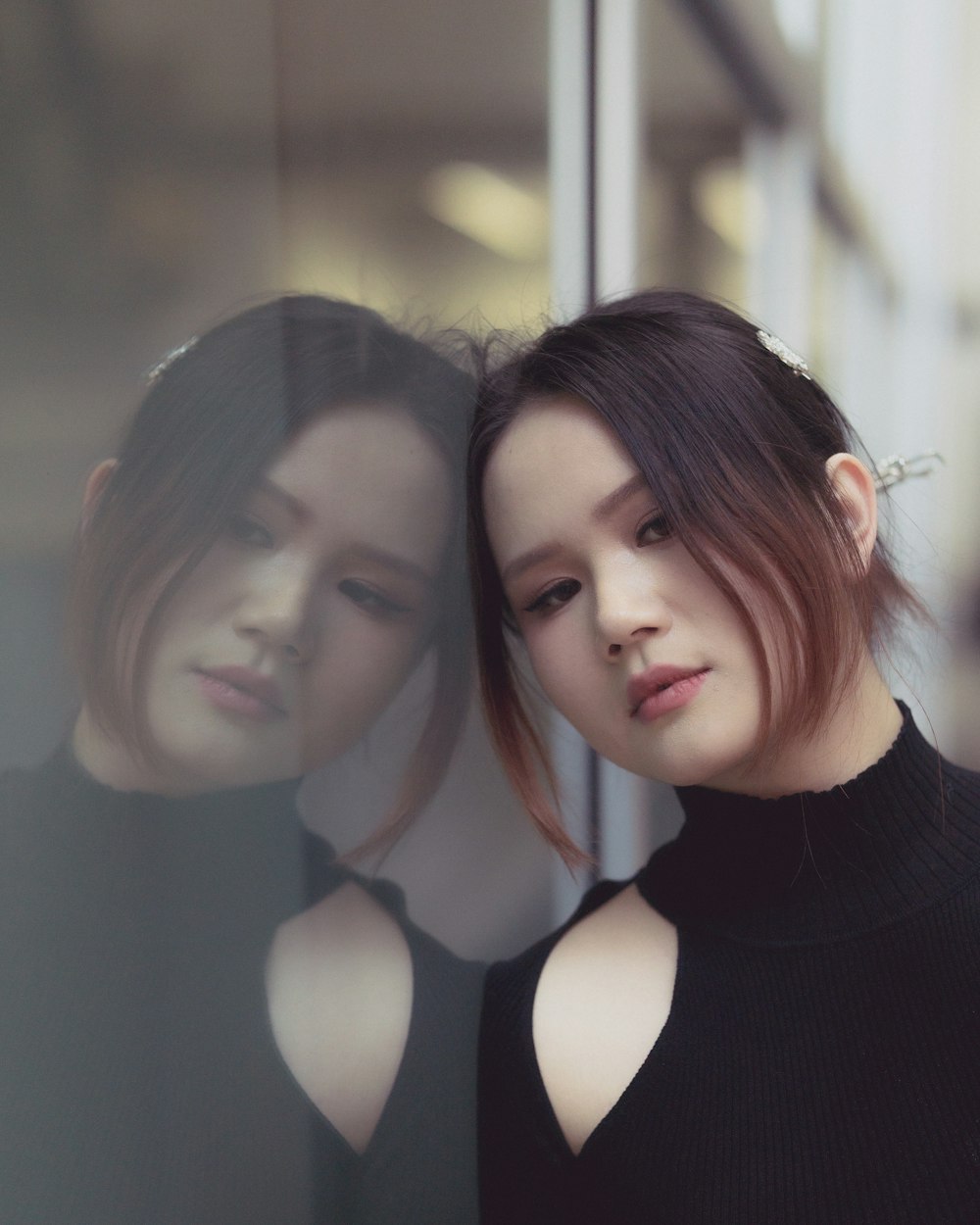 a woman standing in front of a window next to another woman