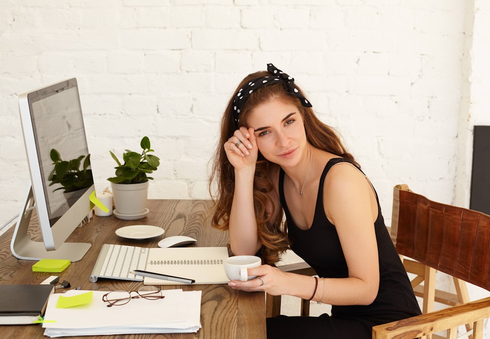 a woman sitting at a desk with a cup of coffee