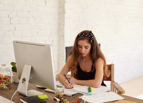 a woman sitting at a desk writing on a piece of paper