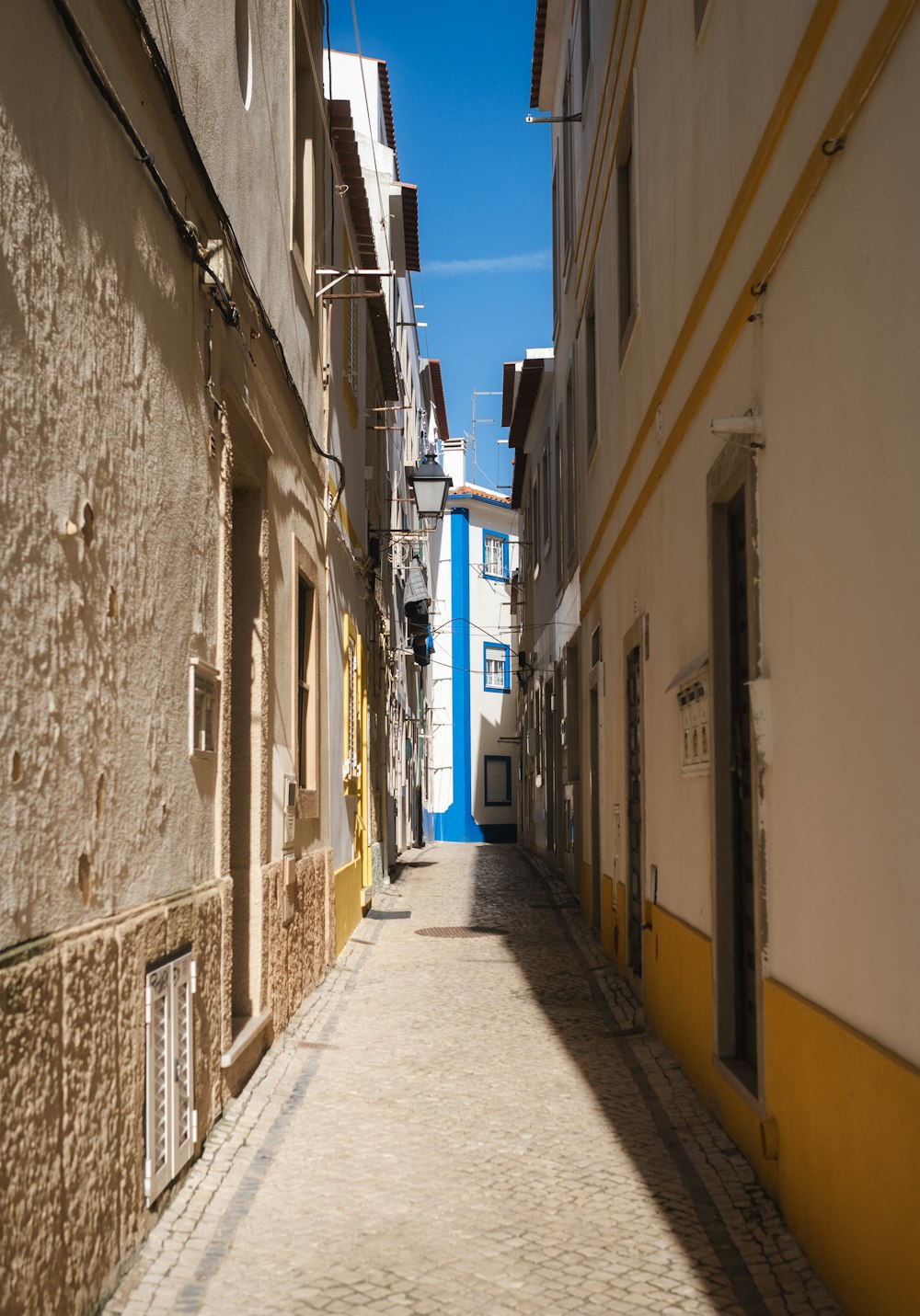 a narrow street with a blue building in the background