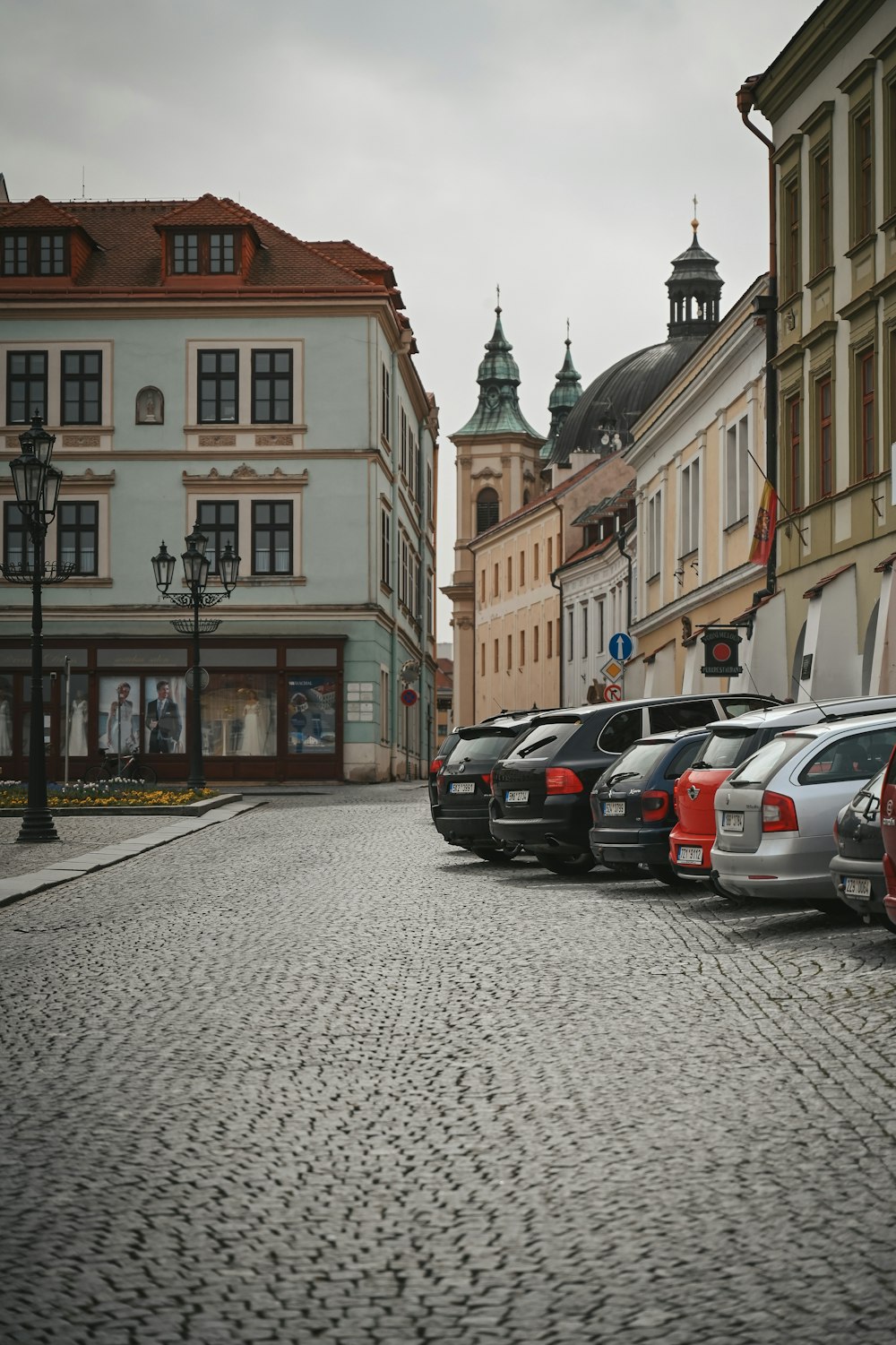 a row of parked cars on a cobblestone street
