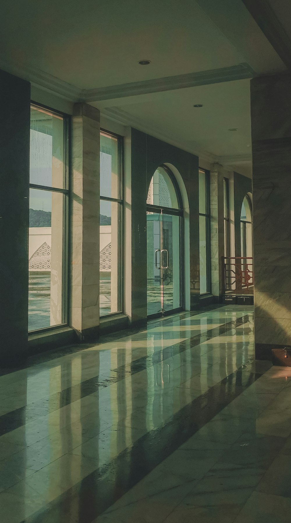 an empty lobby with large windows and marble floors