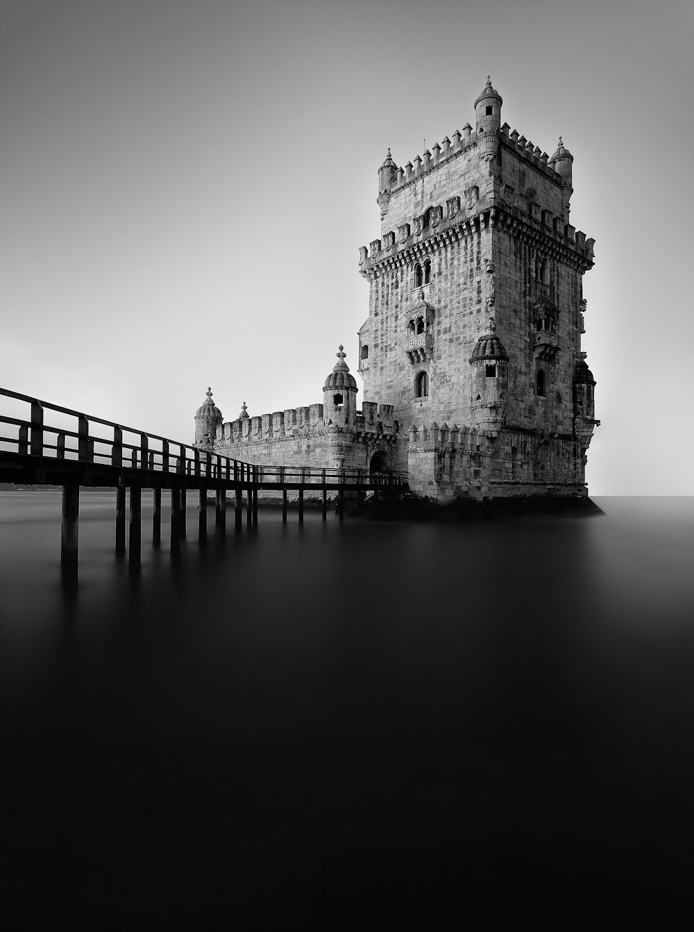 a black and white photo of a pier and a castle