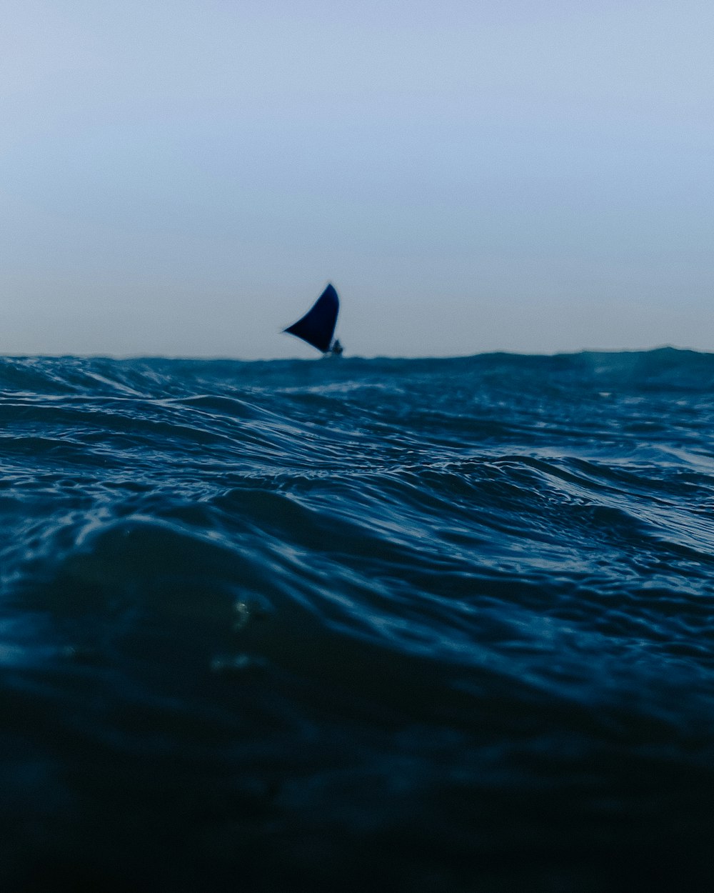 a lone sailboat in the middle of the ocean