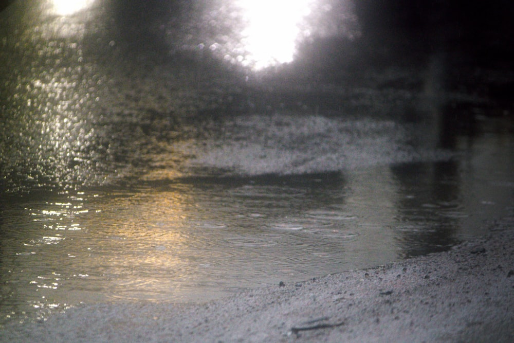 a blurry image of a wet street with a street light in the background