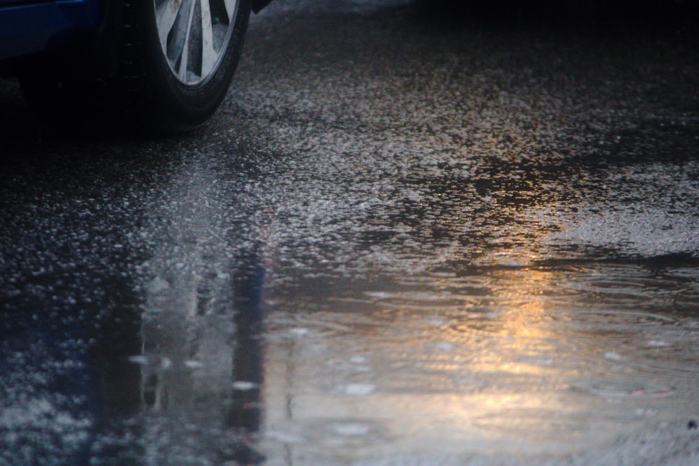 Une voiture bleue roulant dans une rue détrempée par la pluie
