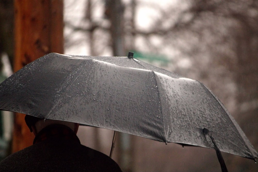 una persona che tiene un ombrello sotto la pioggia