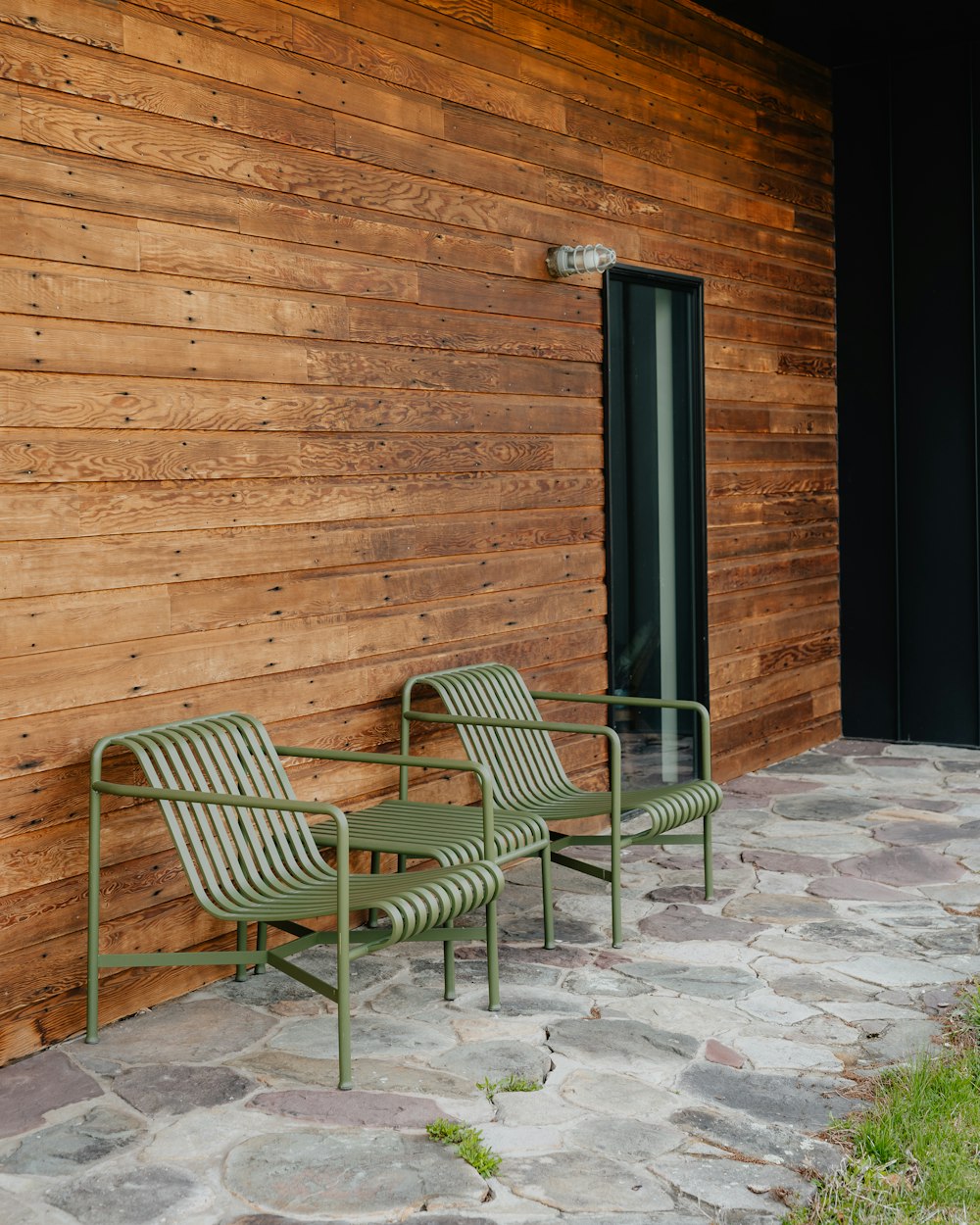 a couple of green chairs sitting next to a wooden building