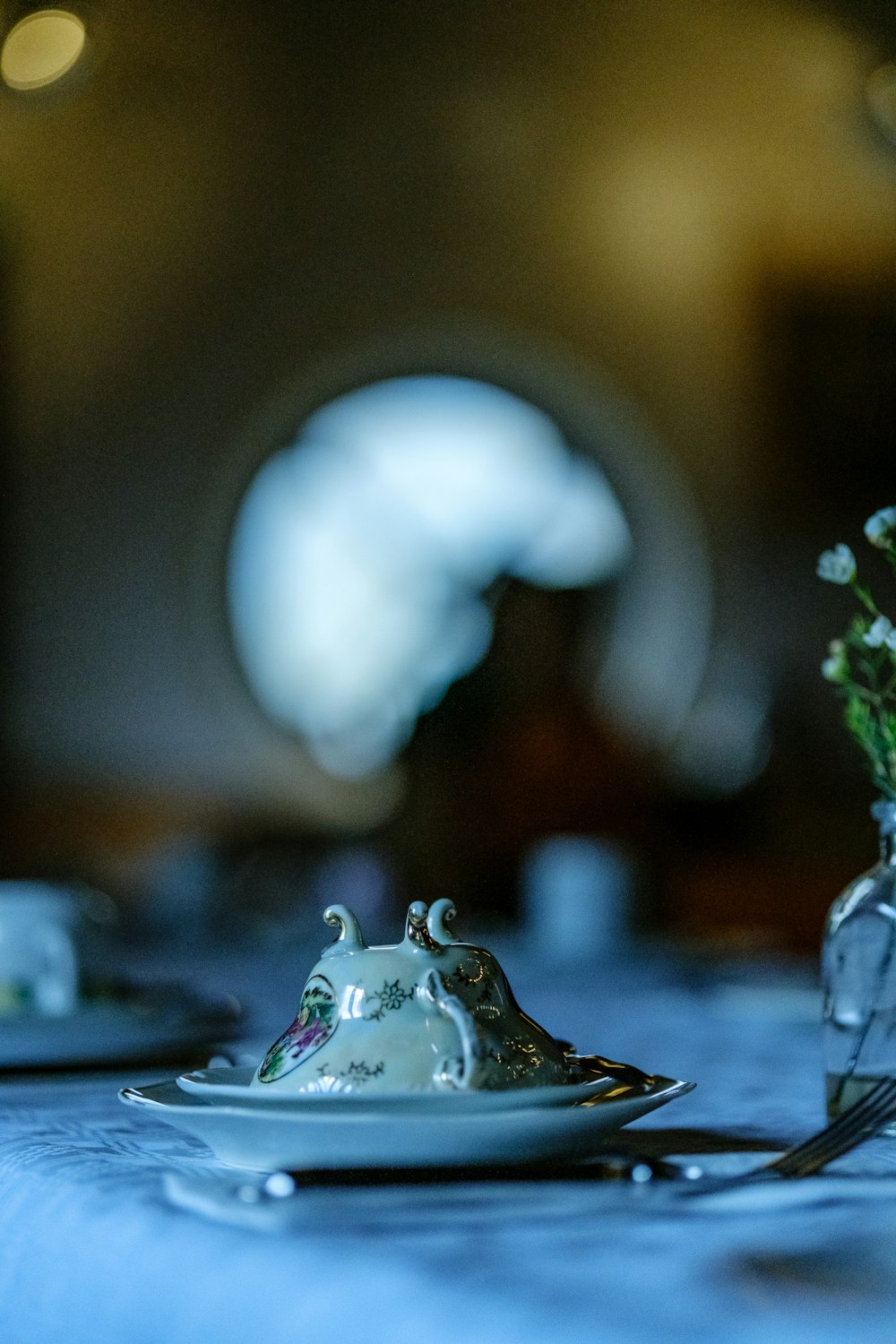 a table with a plate and a vase with flowers on it