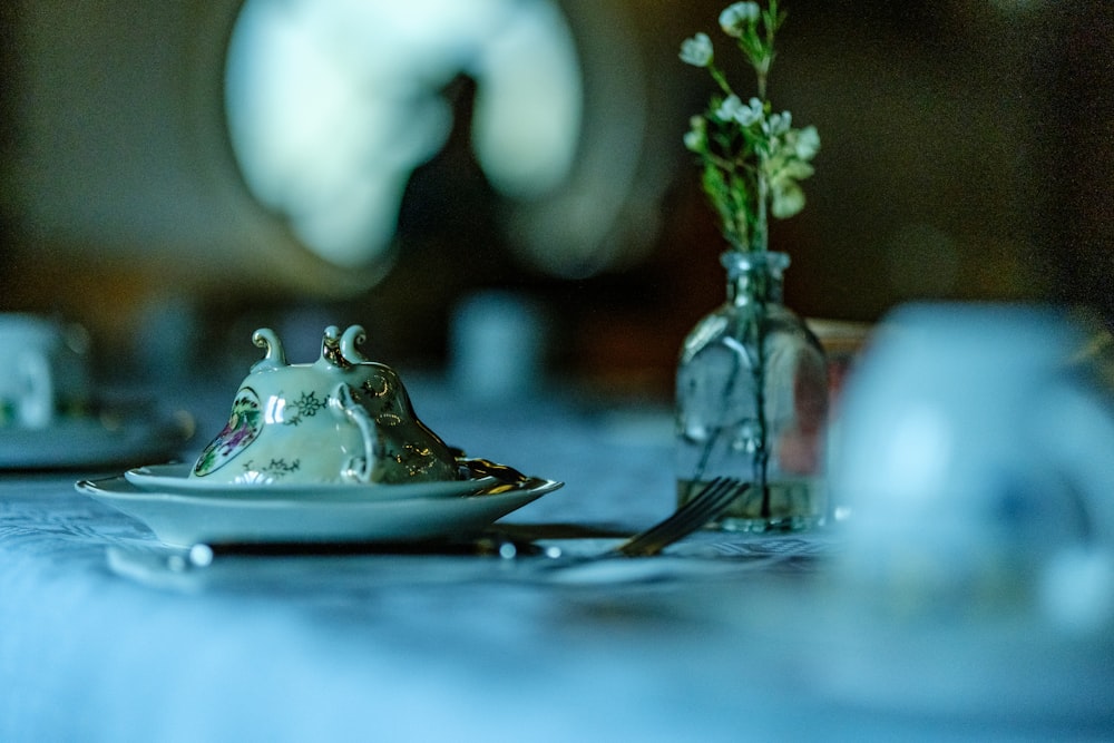 une table avec une assiette et un vase avec des fleurs dessus