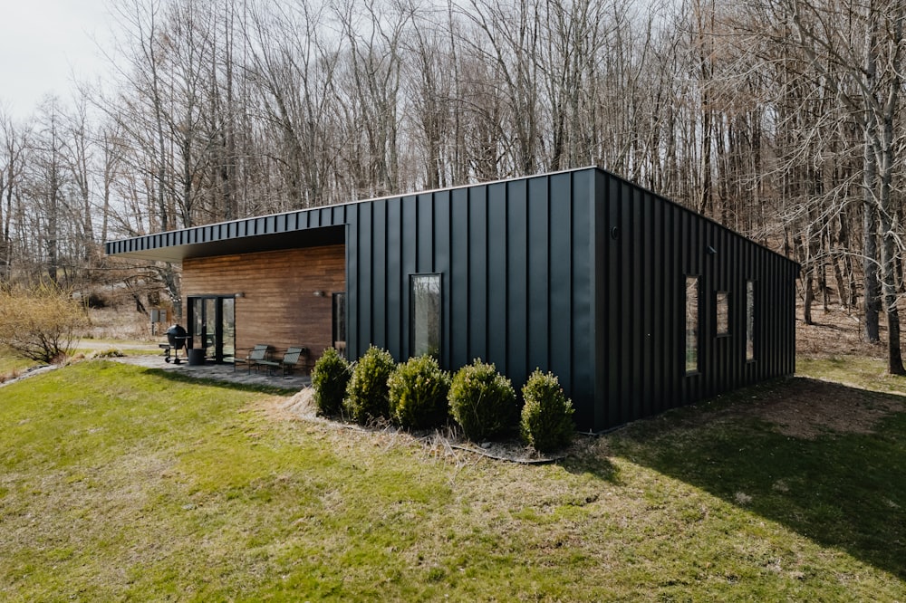 a small black cabin in the middle of a field