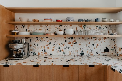 a kitchen counter with a coffee maker and cups on it