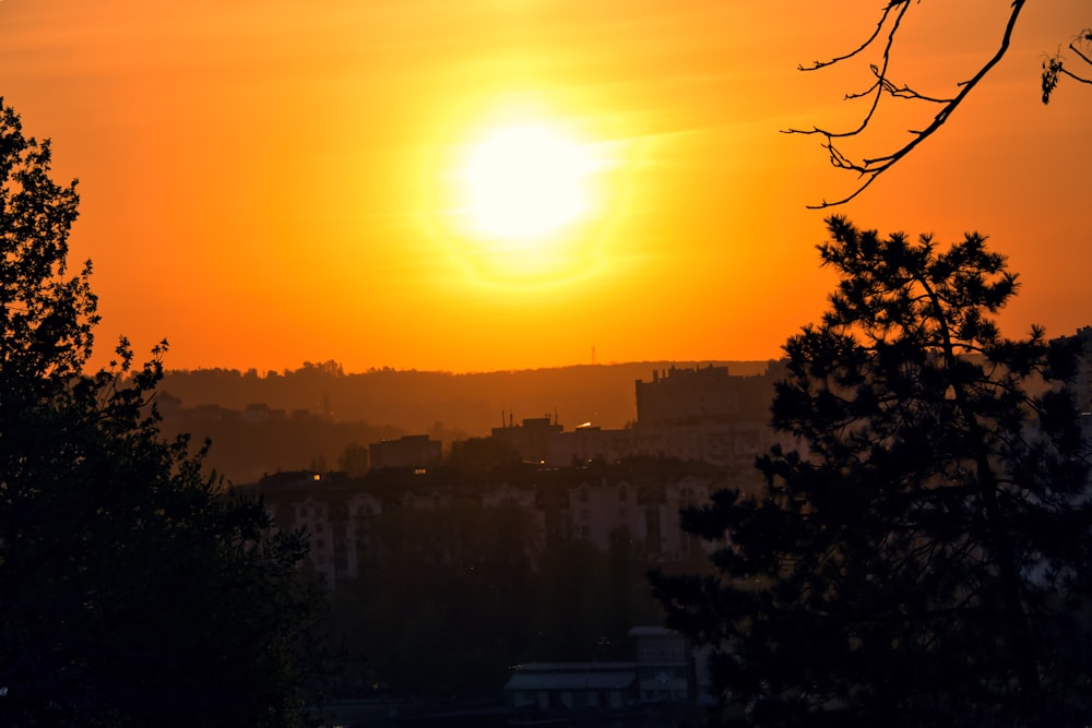 the sun is setting over a city as seen from a hill