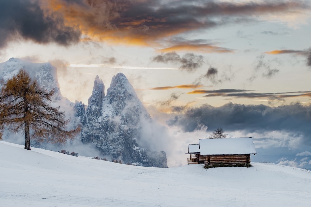 uma cabana na neve com montanhas ao fundo