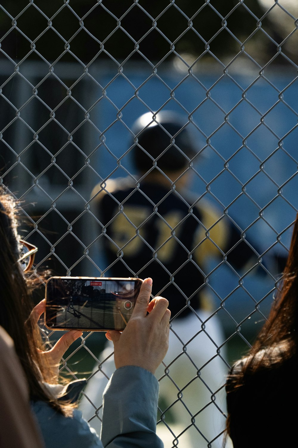 a woman taking a picture of a man behind a fence