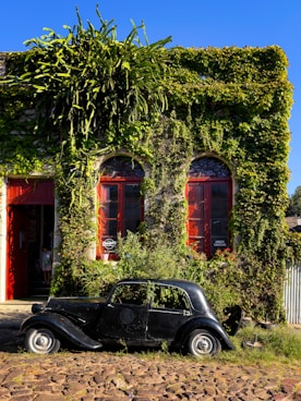 a car parked in front of a building covered in vines