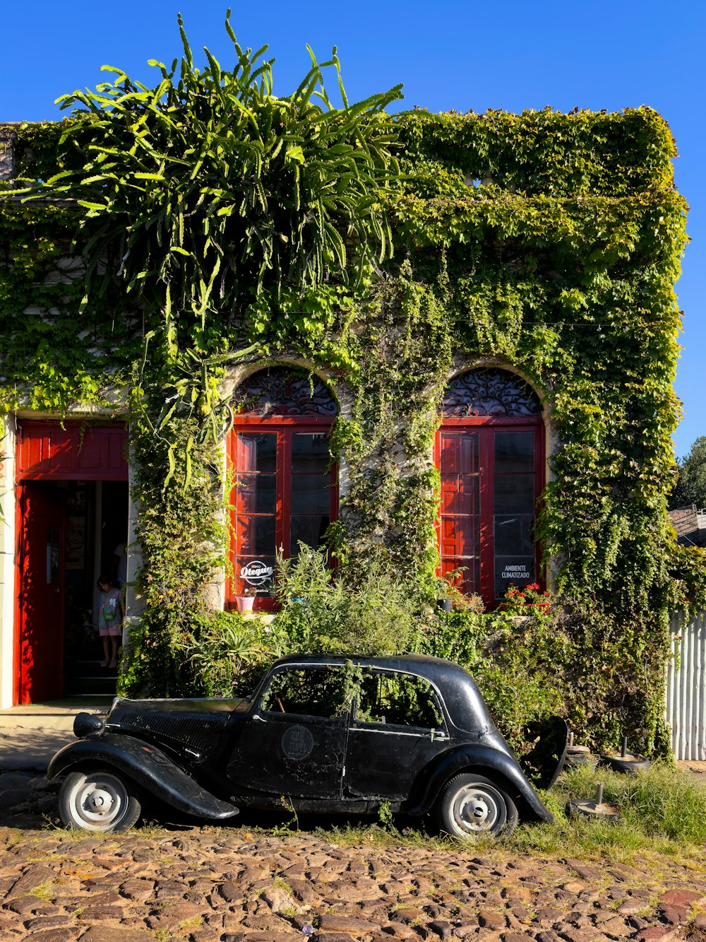 a car parked in front of a building covered in vines