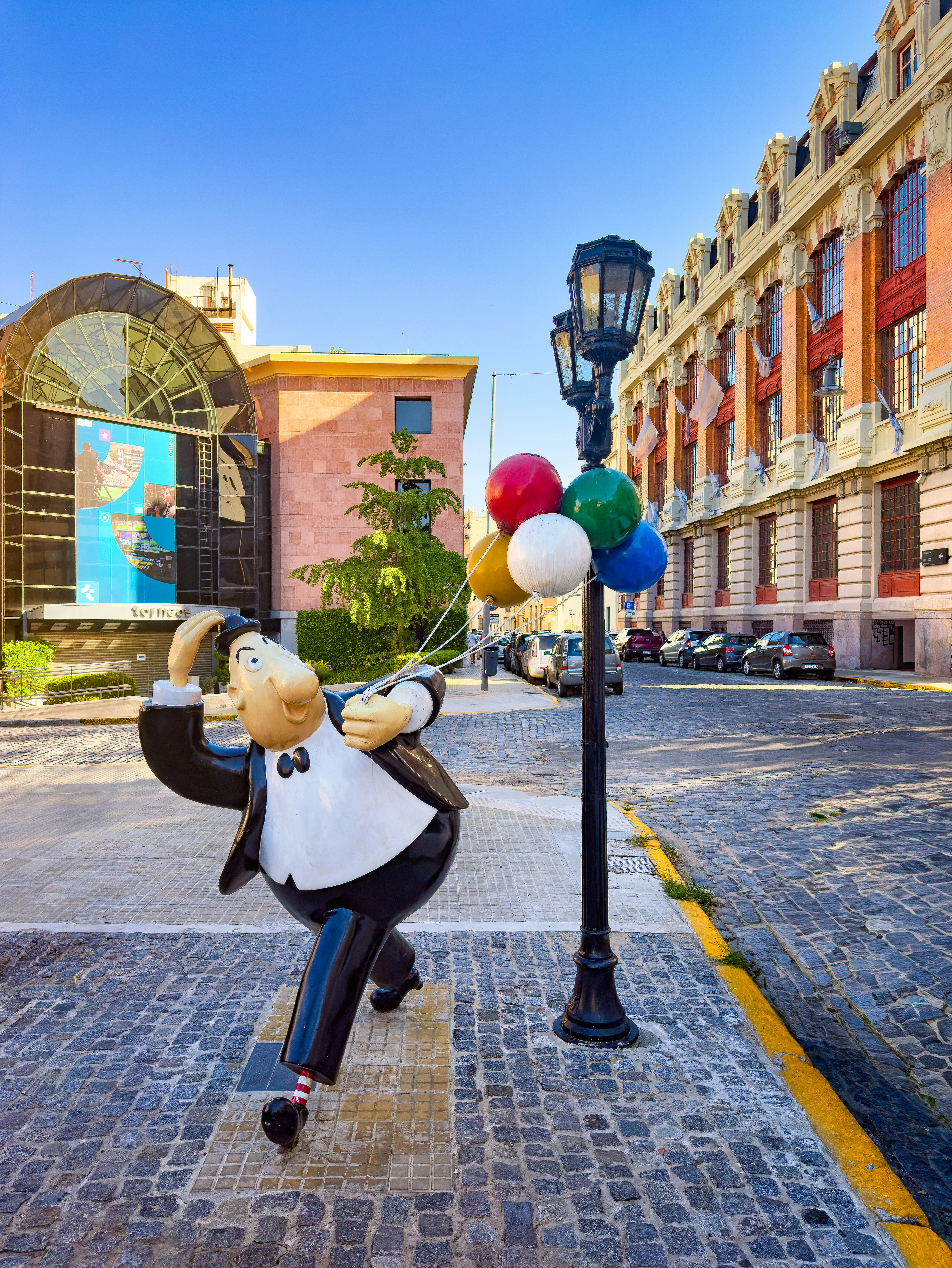 une statue d’un homme tenant un tas de ballons