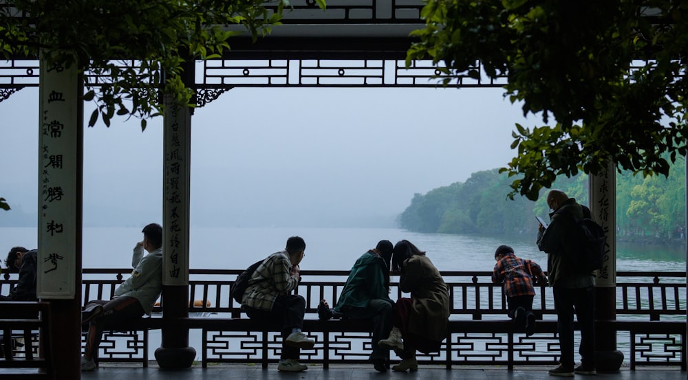 a group of people sitting on a bench next to a body of water