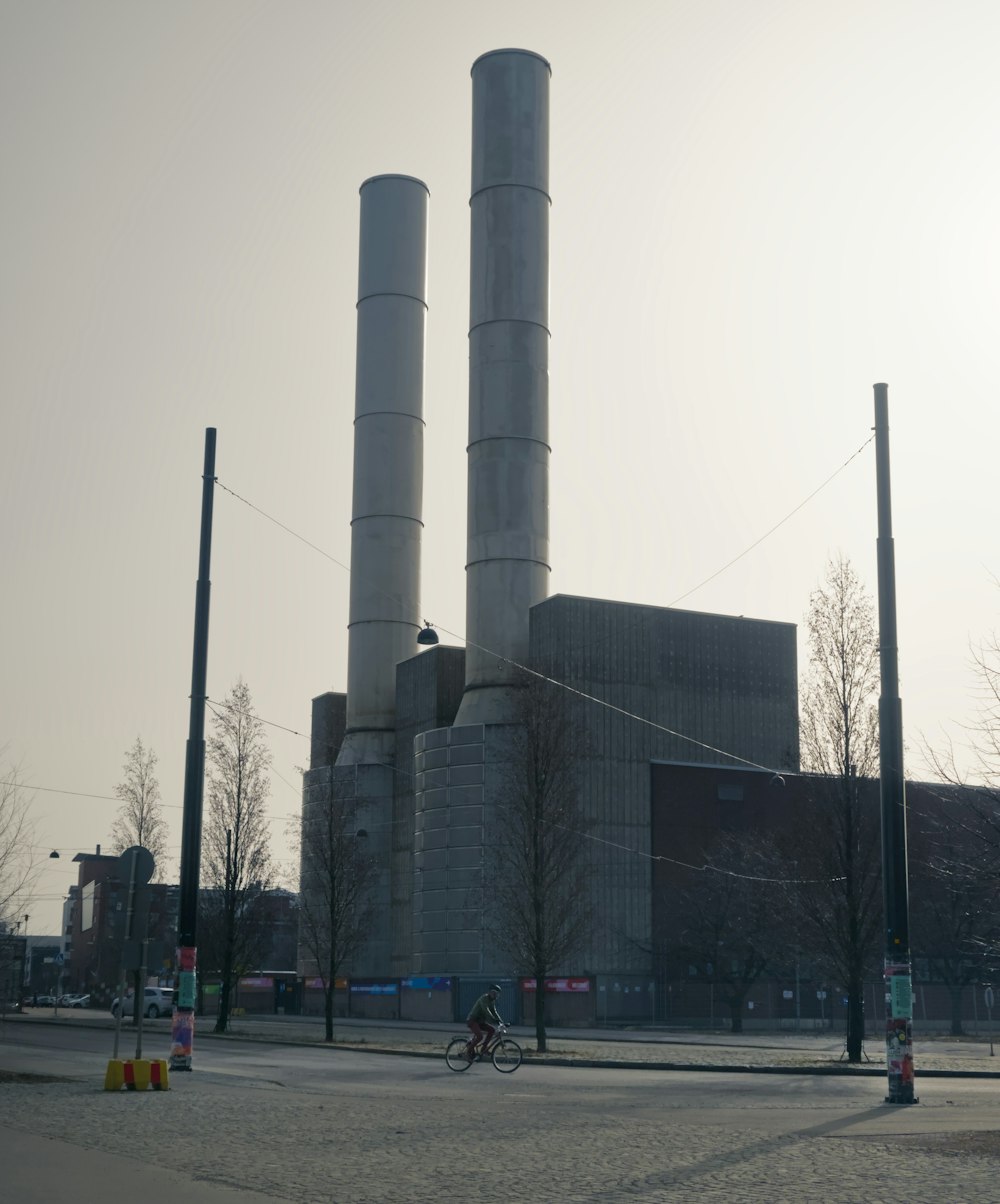 a person riding a bike past a factory