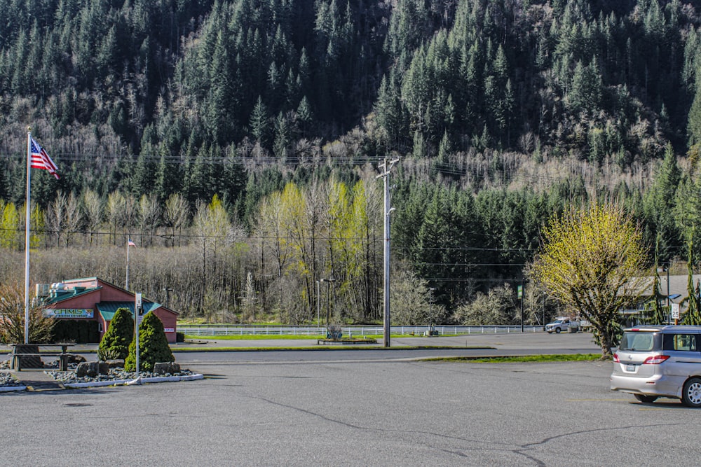 a car parked in a parking lot next to a forest