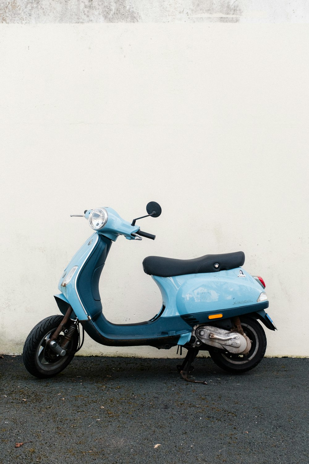 a blue scooter parked next to a white wall