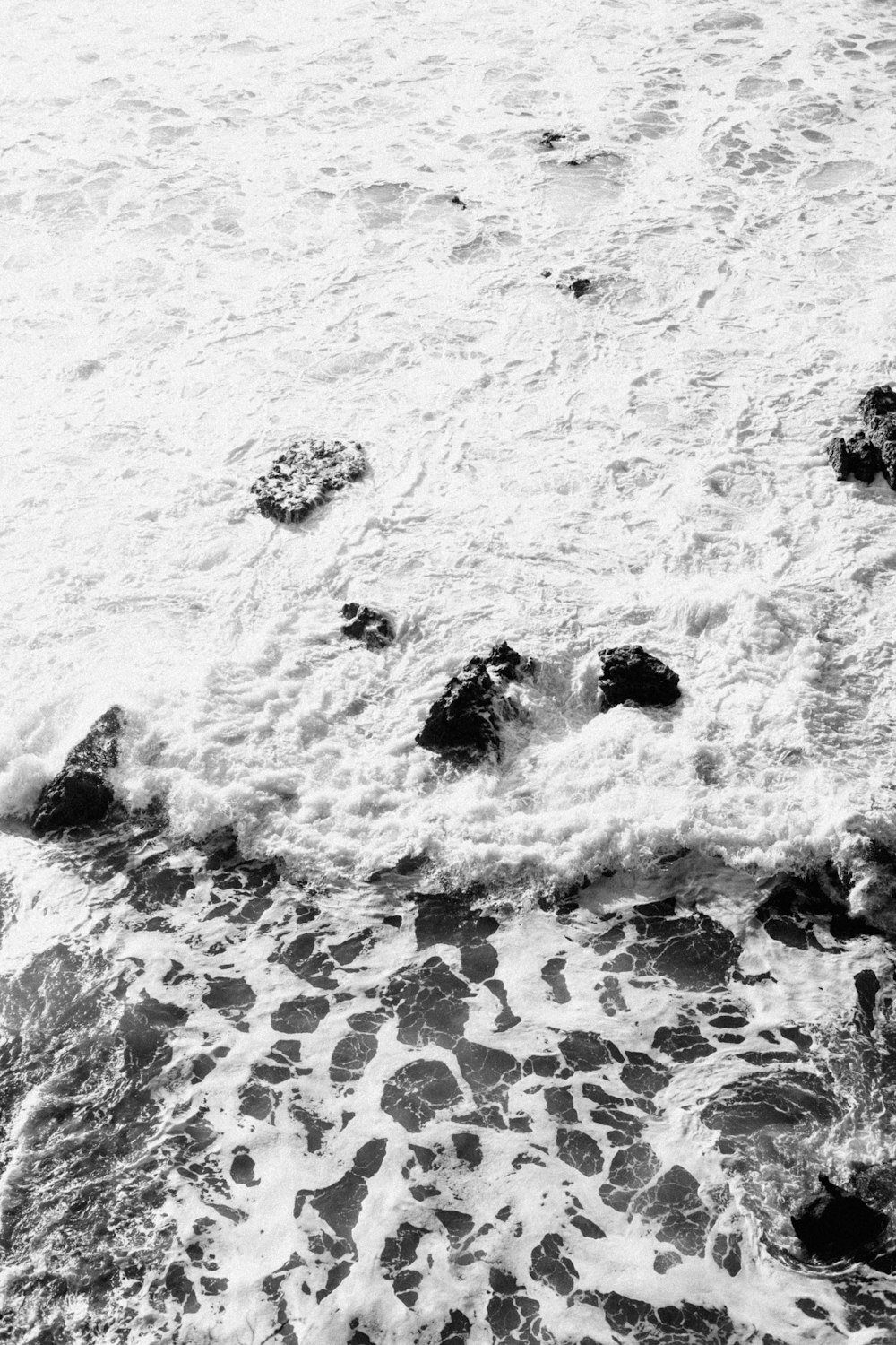 a black and white photo of the ocean and rocks