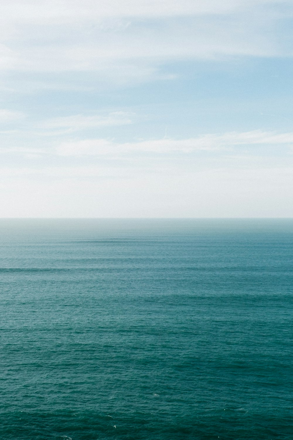 a large body of water sitting under a cloudy blue sky