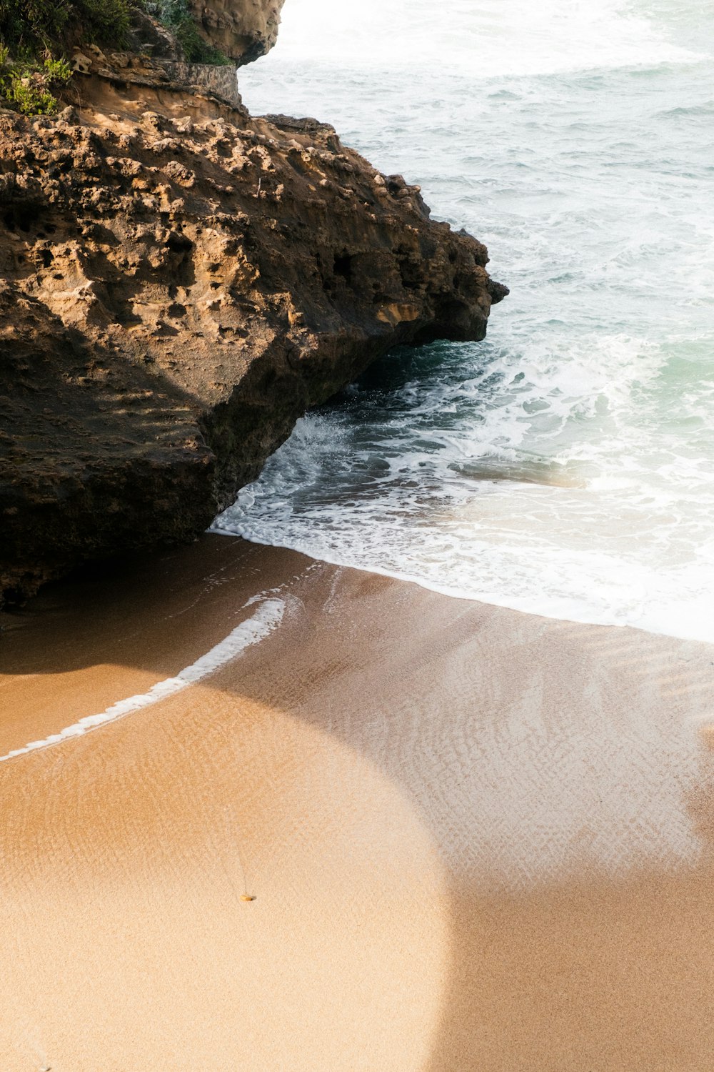 a sandy beach next to the ocean with waves coming in