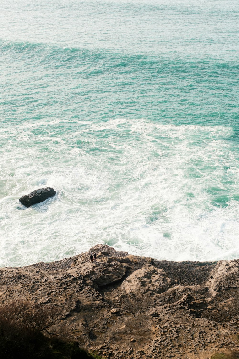 a person sitting on a rock near the ocean