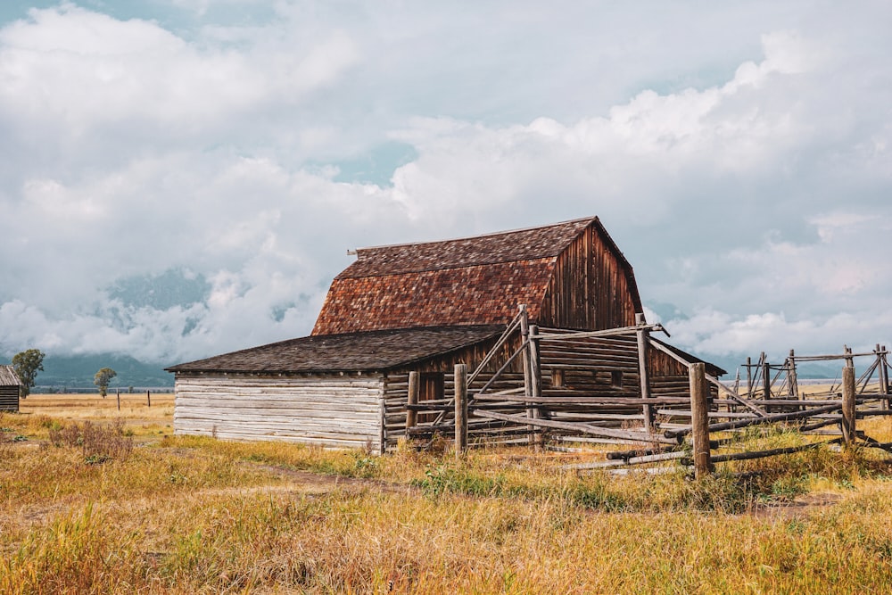 an old barn in a field with a fence