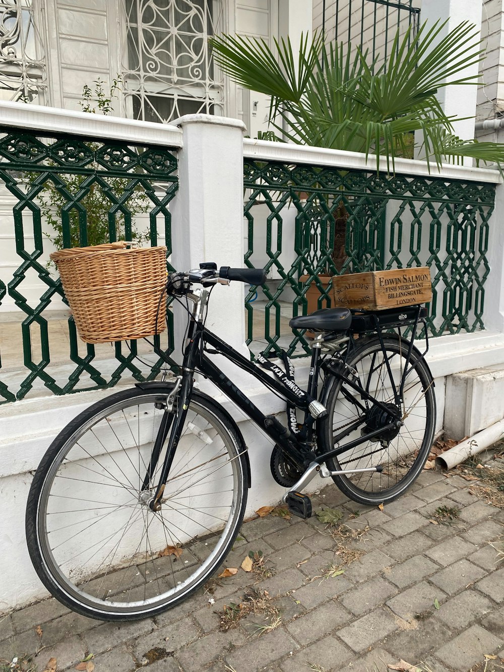 a bicycle parked next to a fence with a basket on it