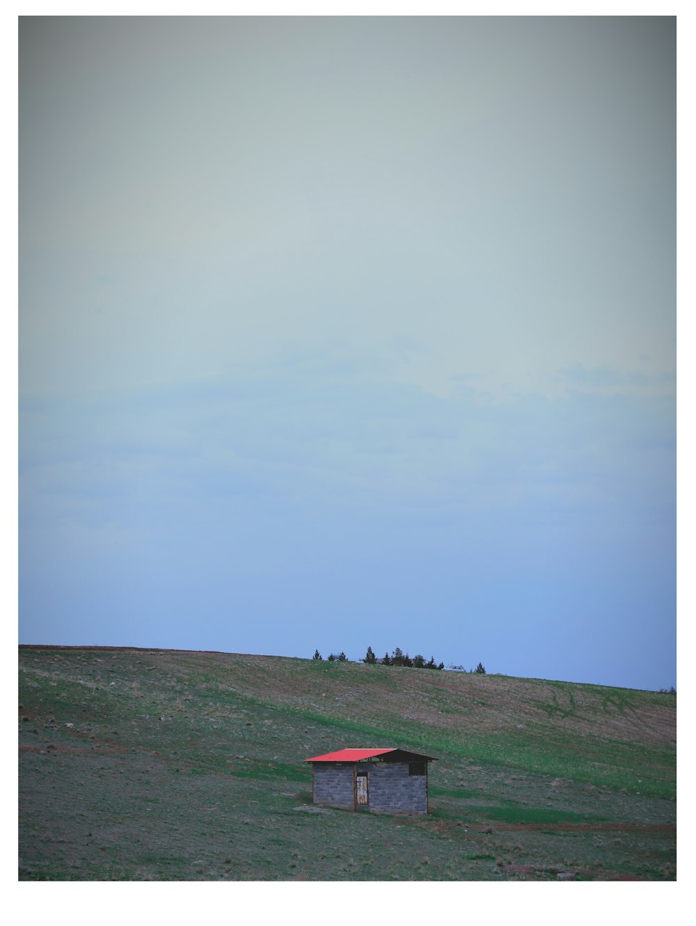 a small shack sitting on top of a lush green field