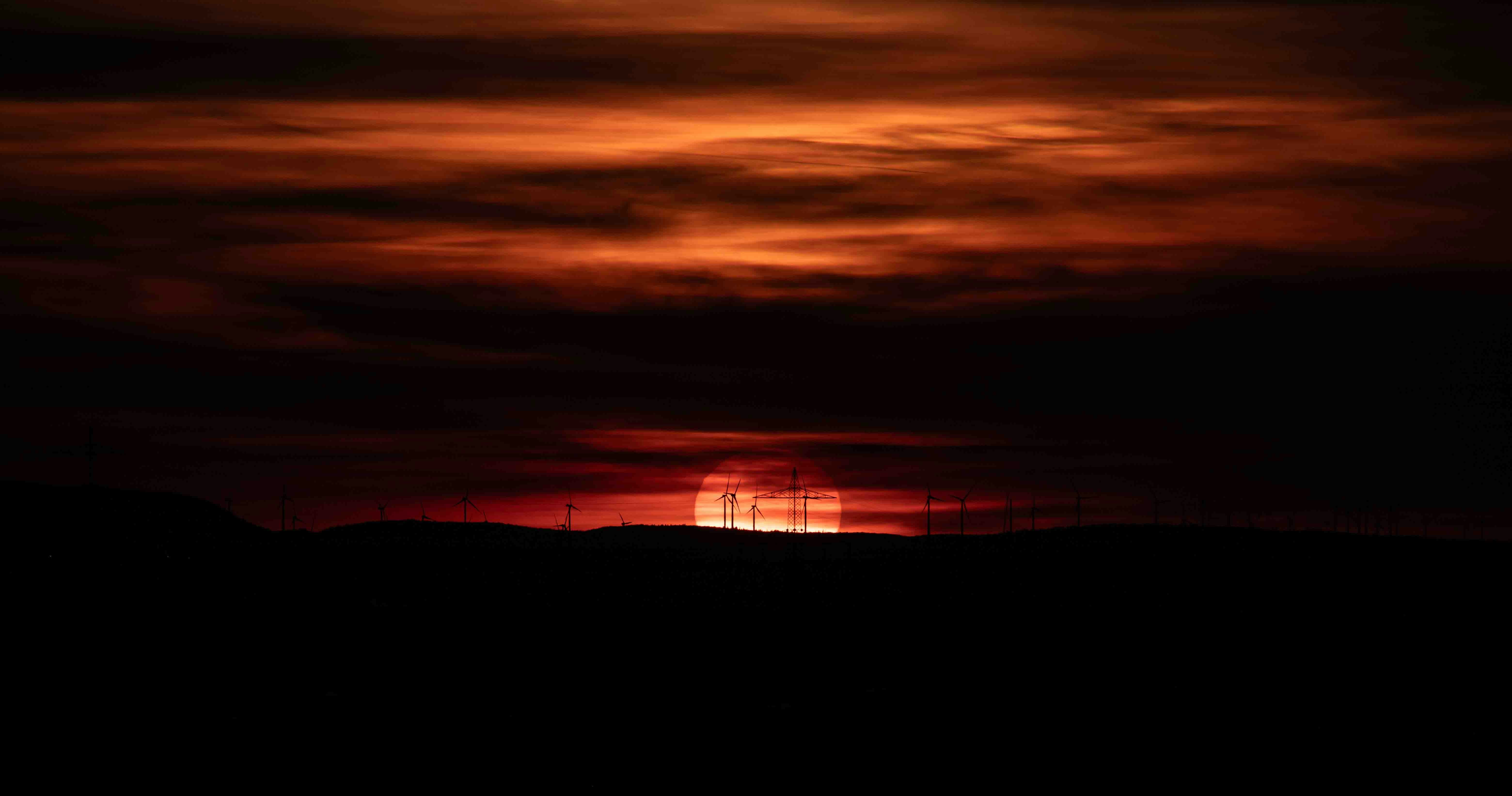 the sun is setting over a hill with barbed wire