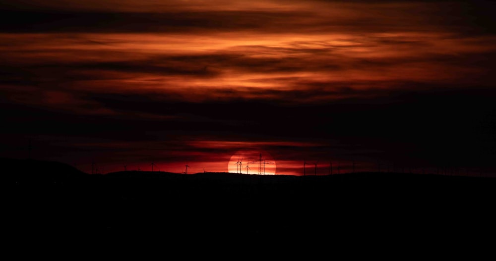 the sun is setting over a hill with barbed wire