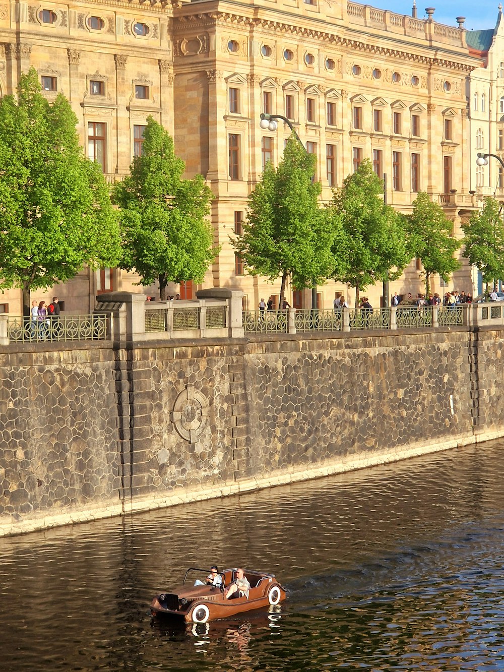 a small boat floating on top of a river next to a tall building