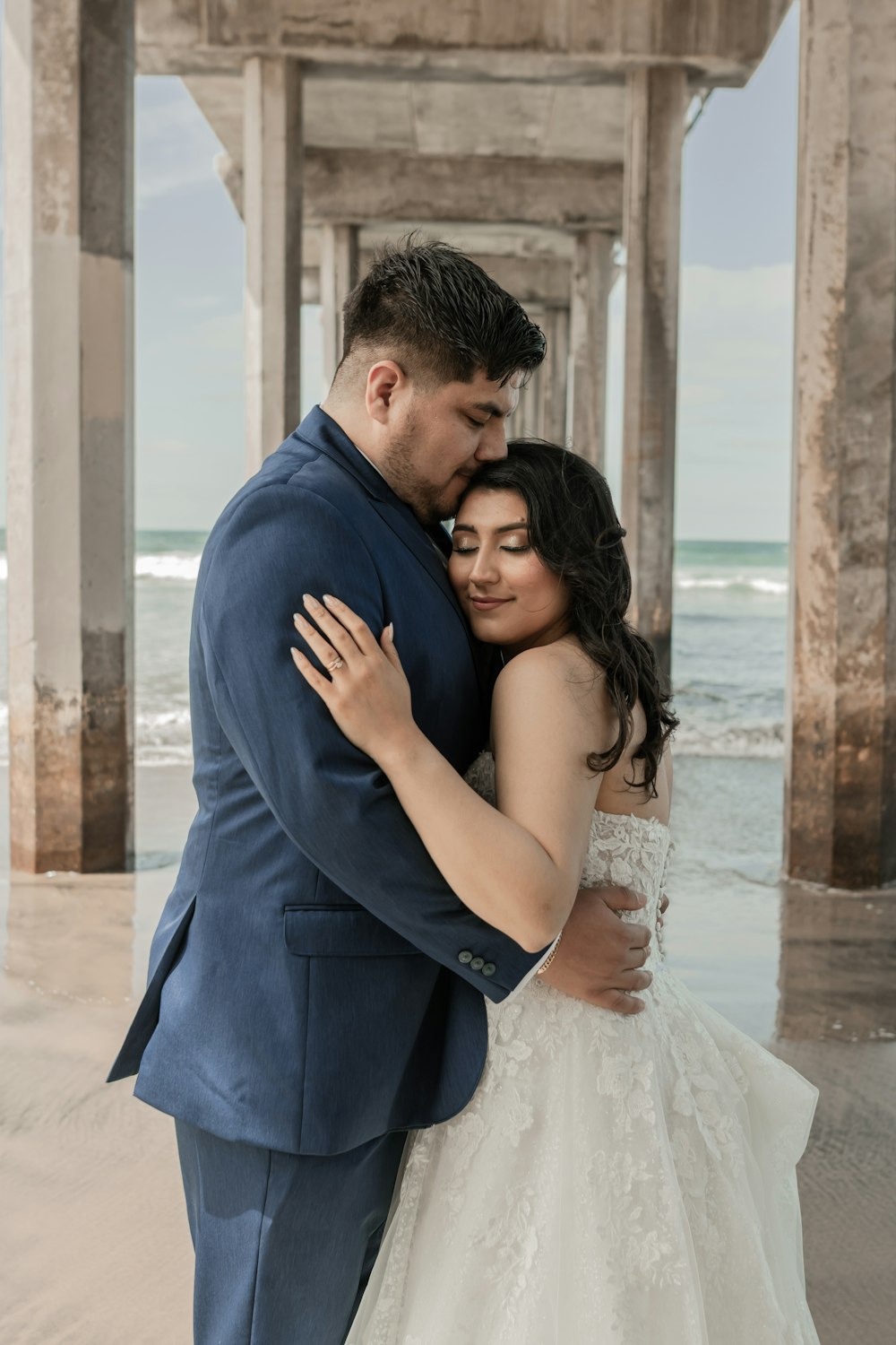 a bride and groom embracing under a pier