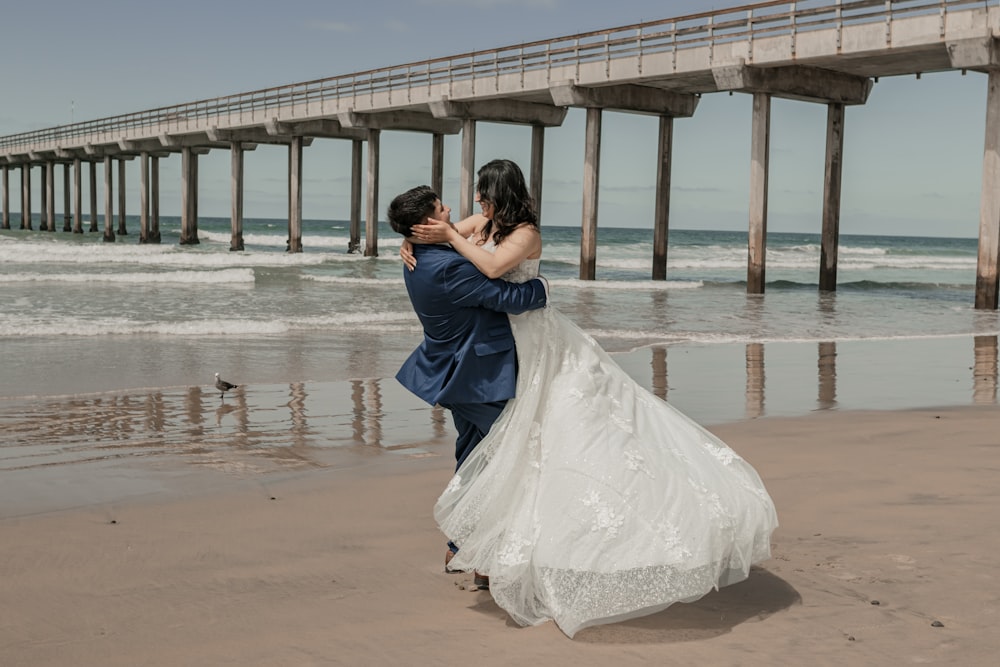 a bride and groom kissing on the beach