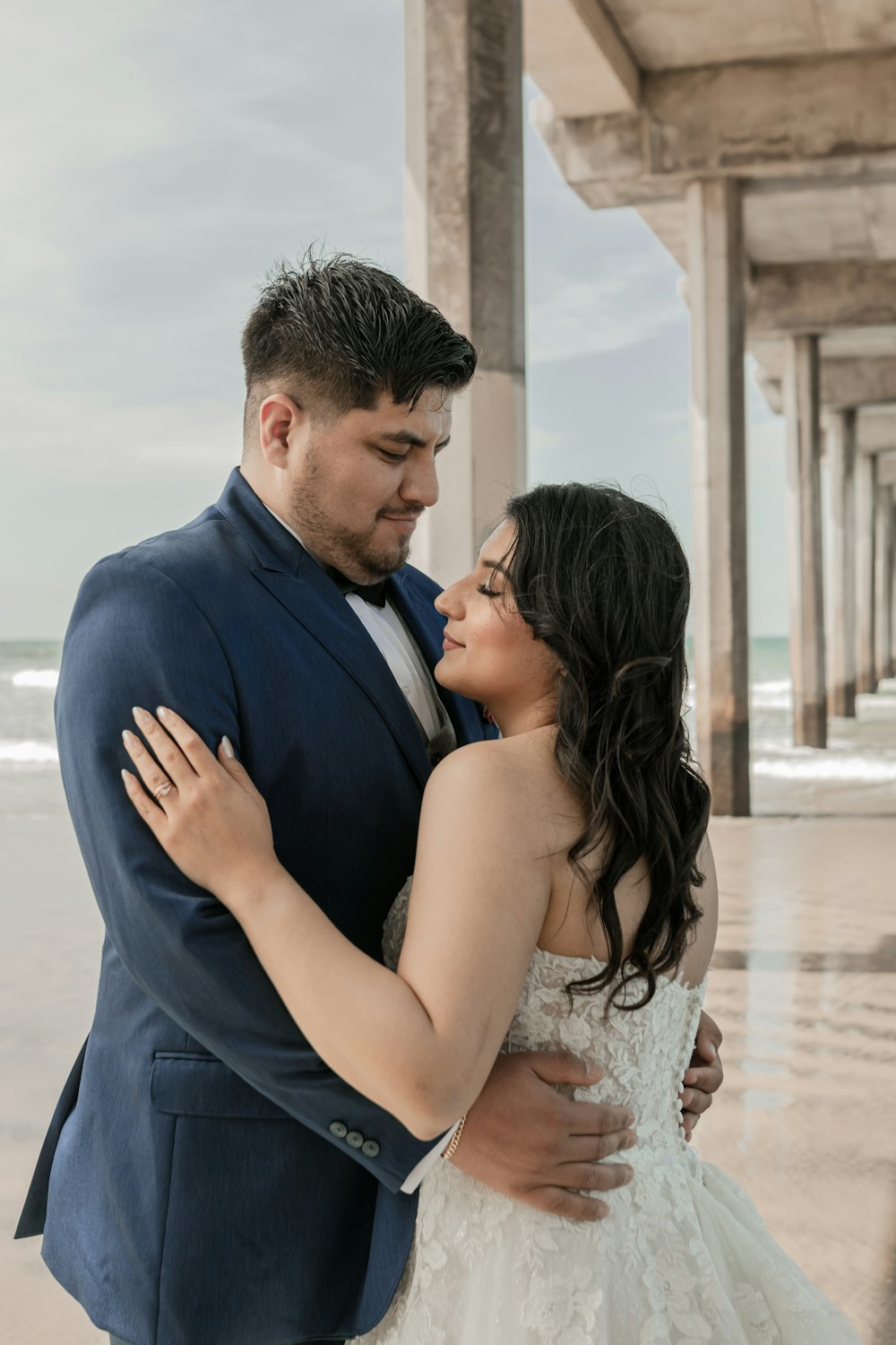 a bride and groom embracing under a pier