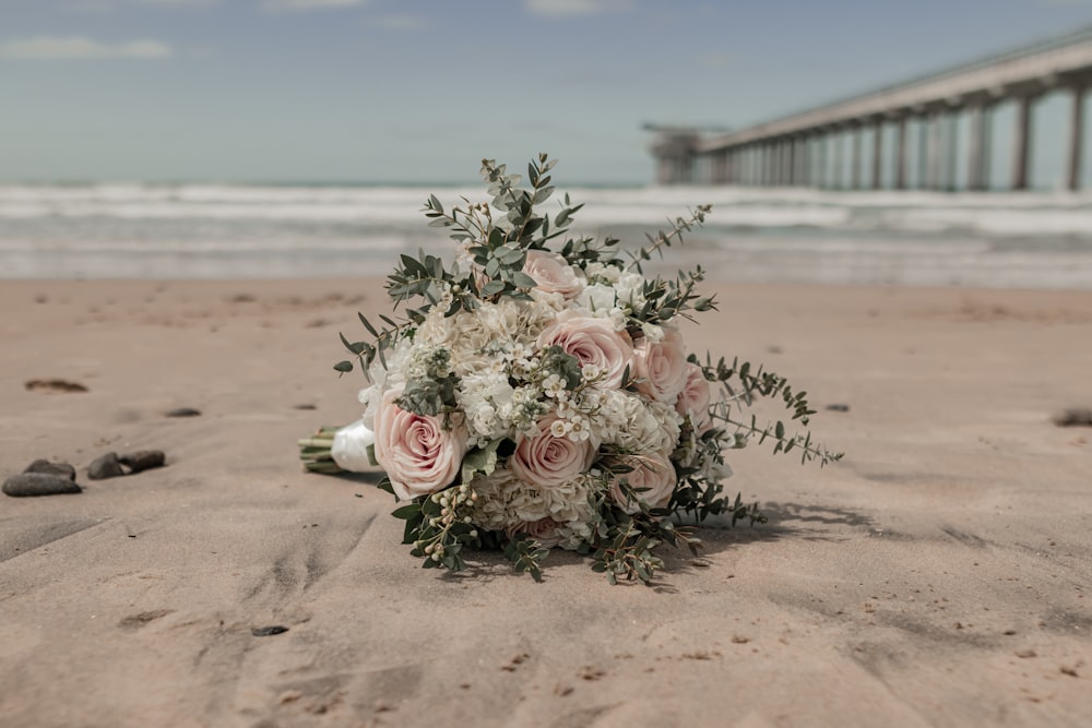 a bouquet of flowers on a beach near the ocean
