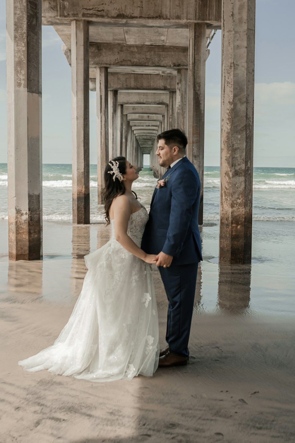 a bride and groom standing under a pier